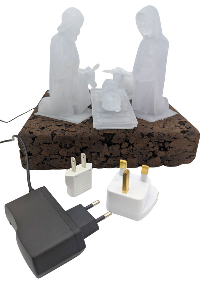 White nativity scene on a cork base with electrical plugs and sockets.