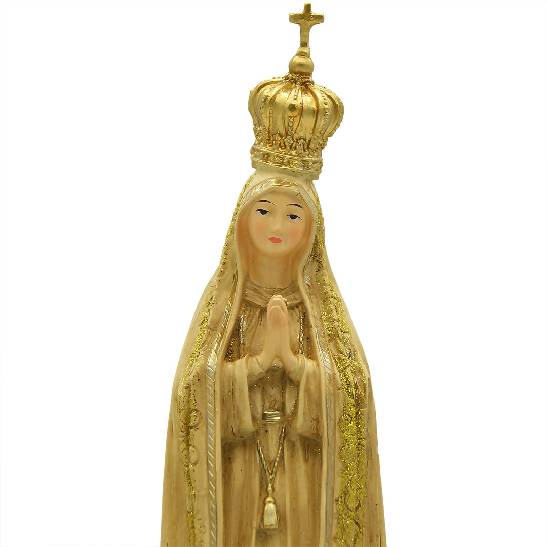 This Our Lady of Fatima statue is made in Fatima, Portugal by the hands of the same artisans that craft the statues of the Shrine of Fatima. The impressive craftsmanship and attention to detail give it a wooden look-alike appearance, although it's made from resin. The figurine sits on a cloud and shows Our Lady wearing a mantle with golden accents painted by hand. On the bottom of the statue it has a music box operated by batteries that plays the Fátima Hymn, Ave.