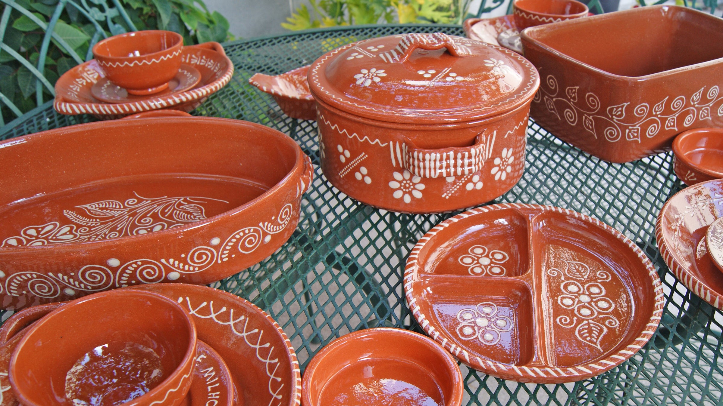 A collection of Barcelos Regional Pottery, made from clay, that are used for cooking hot foods in ovens and stoves, to serve cold foods, and to be used as decorative items. 