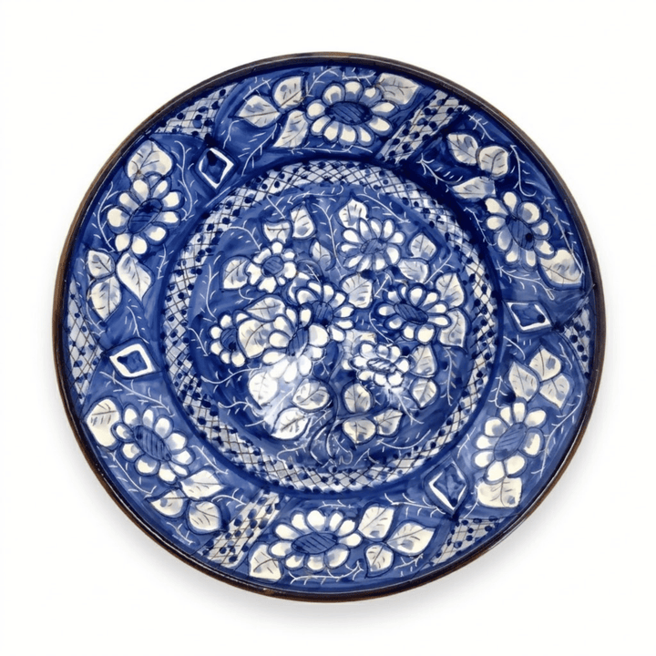 A round ceramic plate with a hand-painted cobalt blue and white floral pattern, photographed from directly above on a white background.