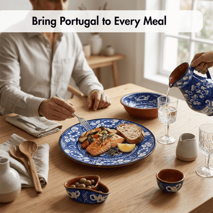A lifestyle dining scene showing a person seated at a wooden table with a blue and white patterned plate of salmon, bread, and vegetables, while another hand pours water from a matching blue and white ceramic pitcher. The text overlay reads &