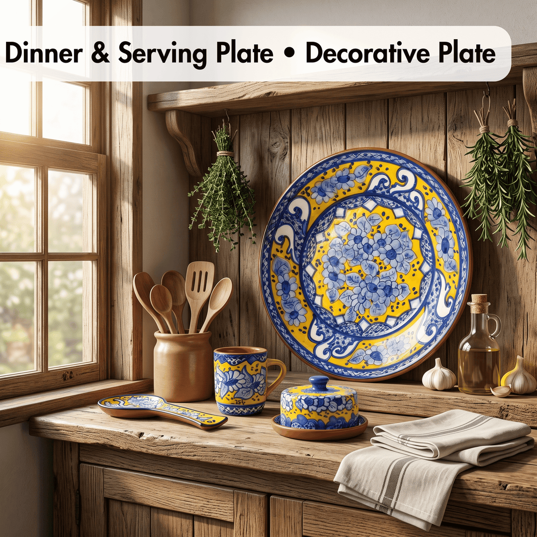 A rustic kitchen scene showing a large decorative ceramic plate with a blue and yellow floral pattern, along with matching serving dishes, utensils, garlic, herbs, and a striped cloth on a wooden counter.