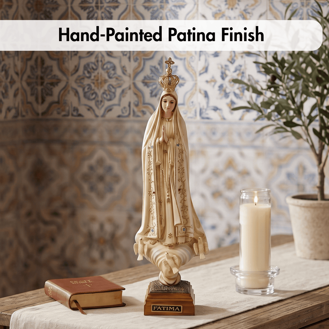 A hand-painted Virgin Mary figurine with a patina finish, displayed on a wooden table alongside a book, a lit candle, and a potted plant against a tiled wall background.