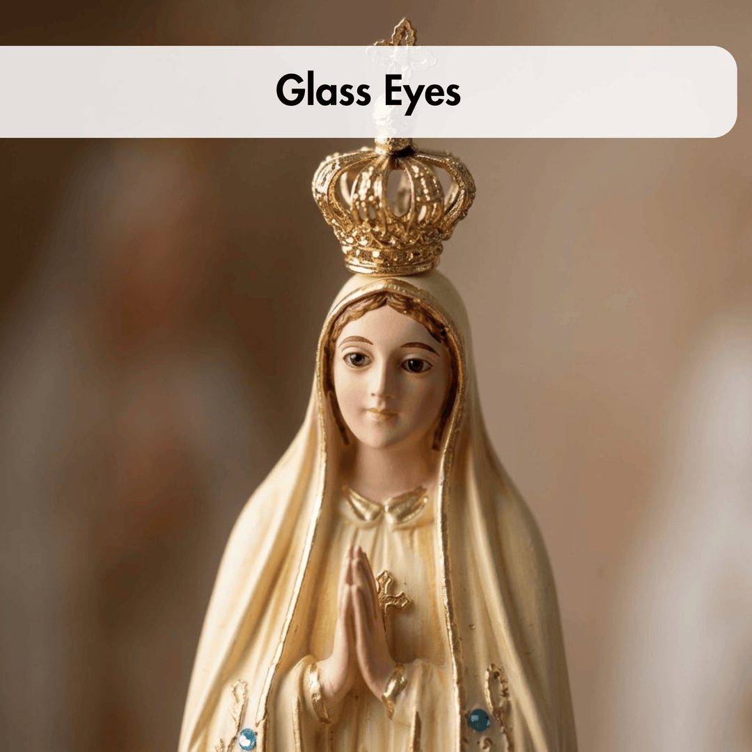 A close-up of a religious figurine with a gold crown and veil, shown against a soft blurred background. A white label at the top reads &