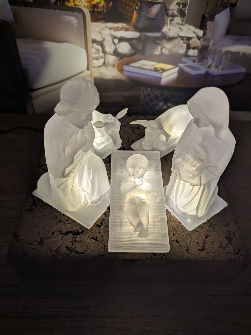 White ceramic nativity scene with three figures on a dark surface