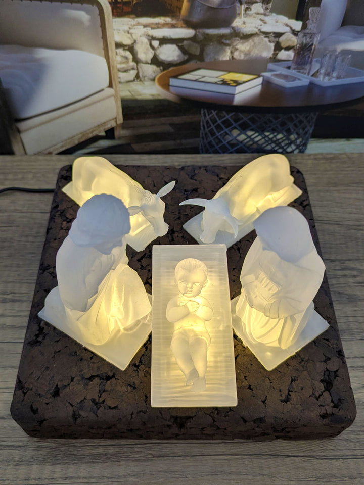 White nativity scene figurines on a dark surface with a blurred background