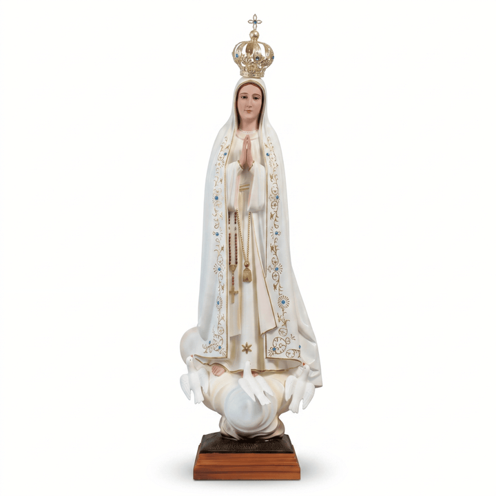 A religious statue of the Virgin Mary standing on a pedestal, wearing a white robe with gold and blue embroidery, a gold crown, and holding a rosary, photographed against a plain white background.