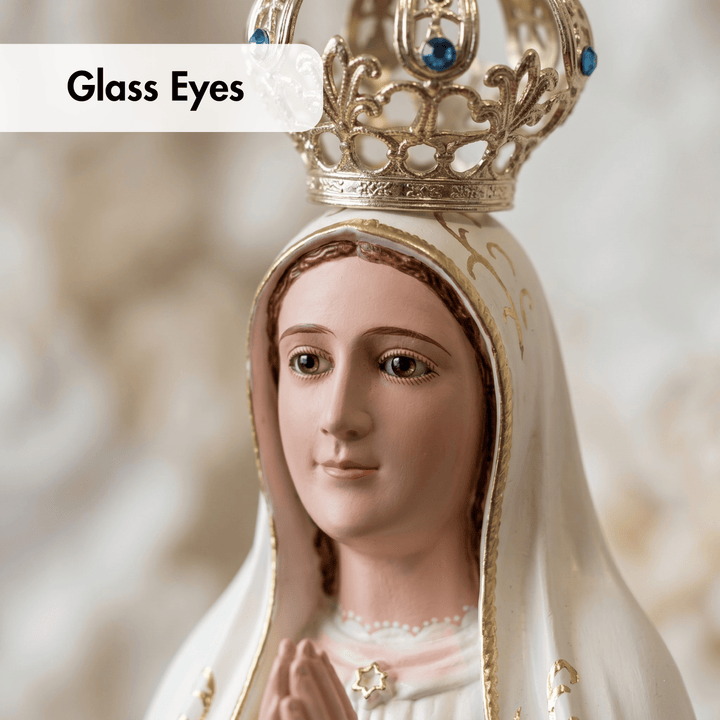 A close-up of a religious figurine or statue of the Virgin Mary wearing a gold crown and white veil, with the text &