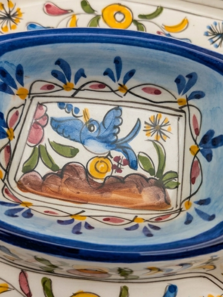Decorative ceramic bowl with floral patterns and a bird illustration on a white background