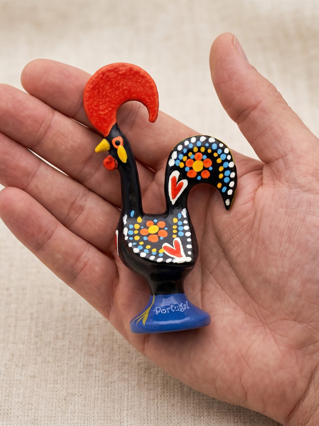 Decorative rooster figurine held in a hand against a beige background