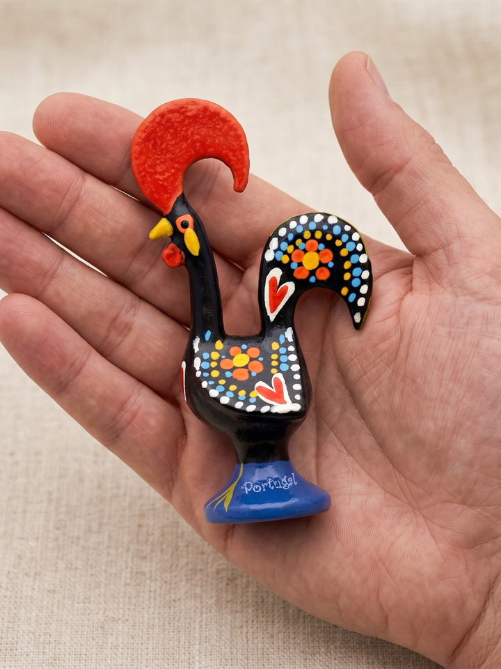 Decorative rooster figurine held in a hand against a beige background