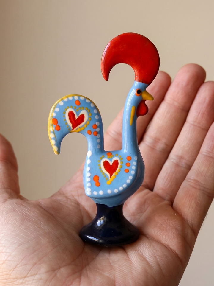 Decorative rooster figurine with red comb held in a hand against a beige background