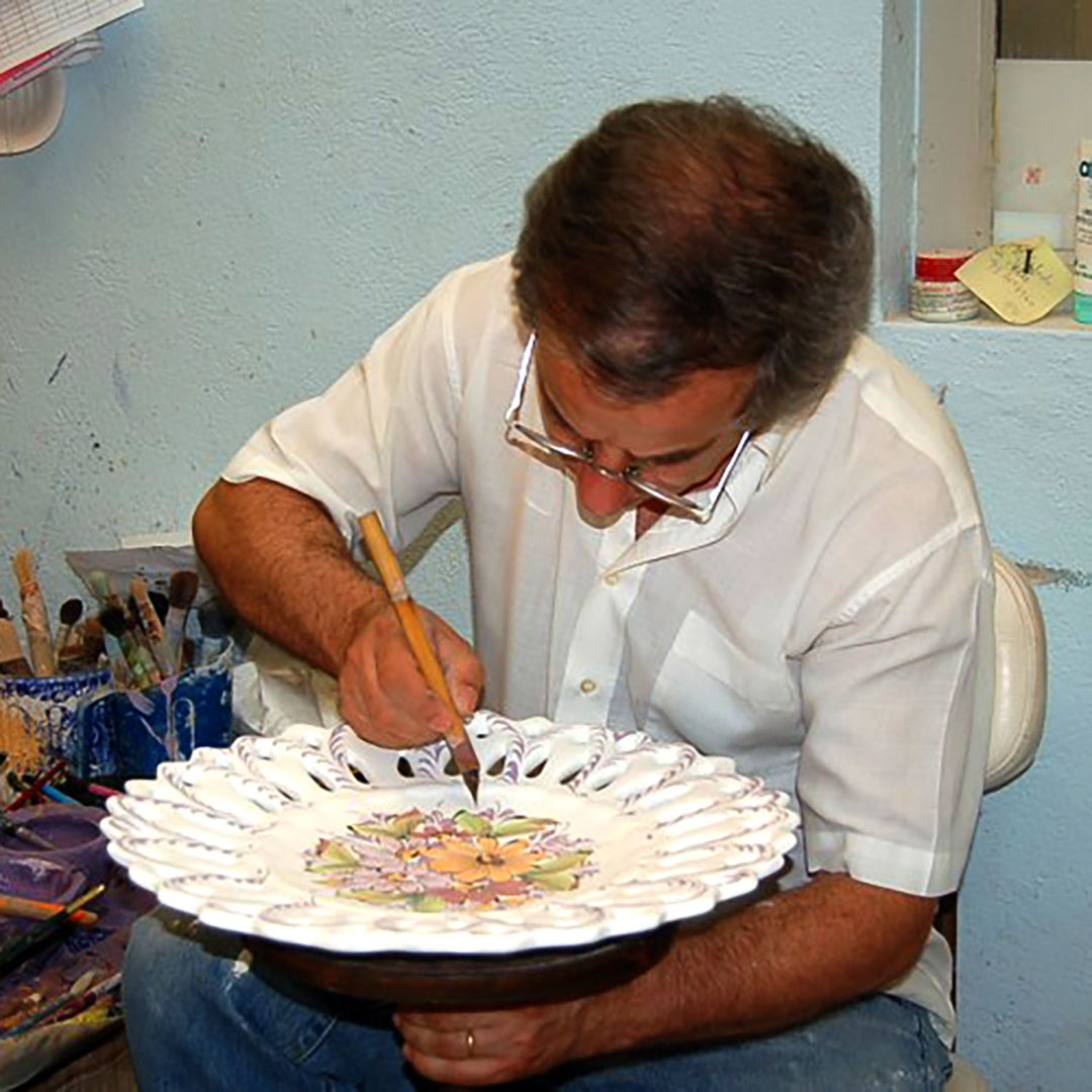 Portuguese artisans hand painting a traditional Alcobaca ceramic plate.