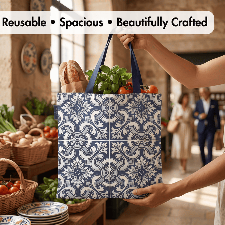 A reusable tote bag with a blue and white floral tile pattern is being held by a person in a market setting, filled with groceries like bread, basil, and tomatoes. Text at the top reads &