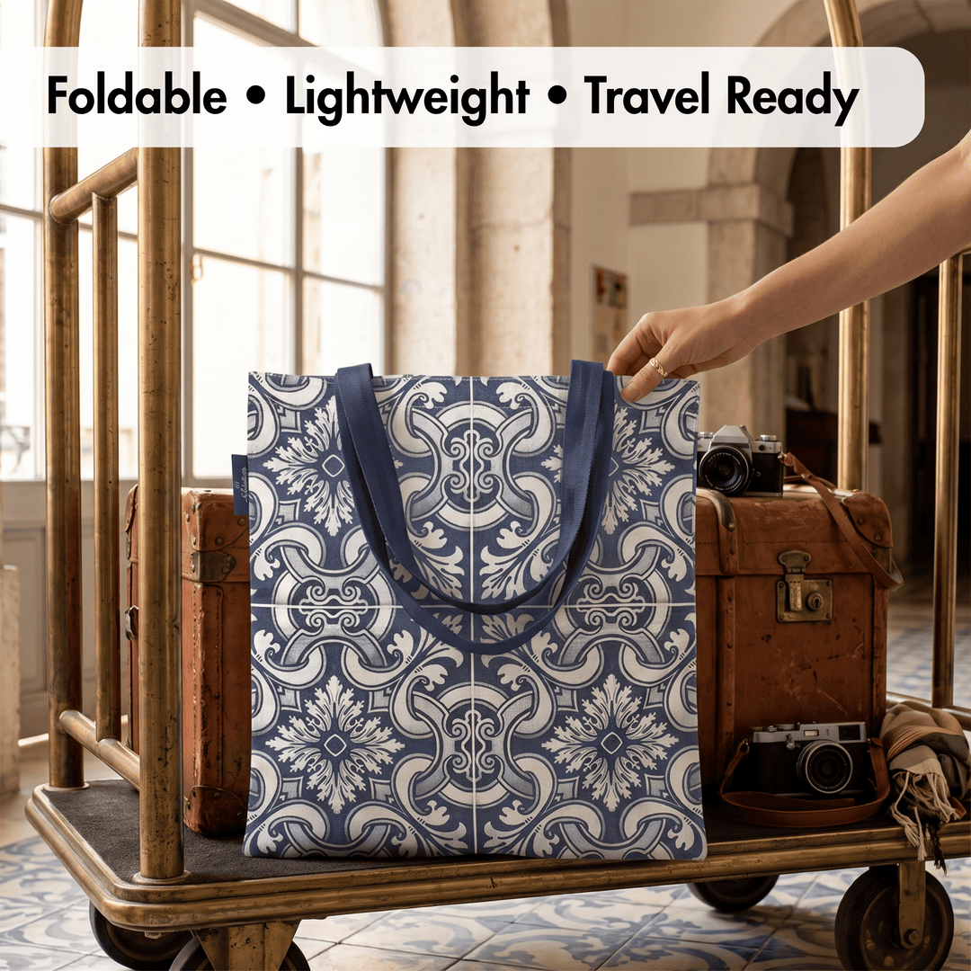 A blue and white patterned foldable tote bag with dark blue handles is shown on a vintage luggage cart in a travel-themed setting. A hand is holding the bag, and a text overlay at the top reads &