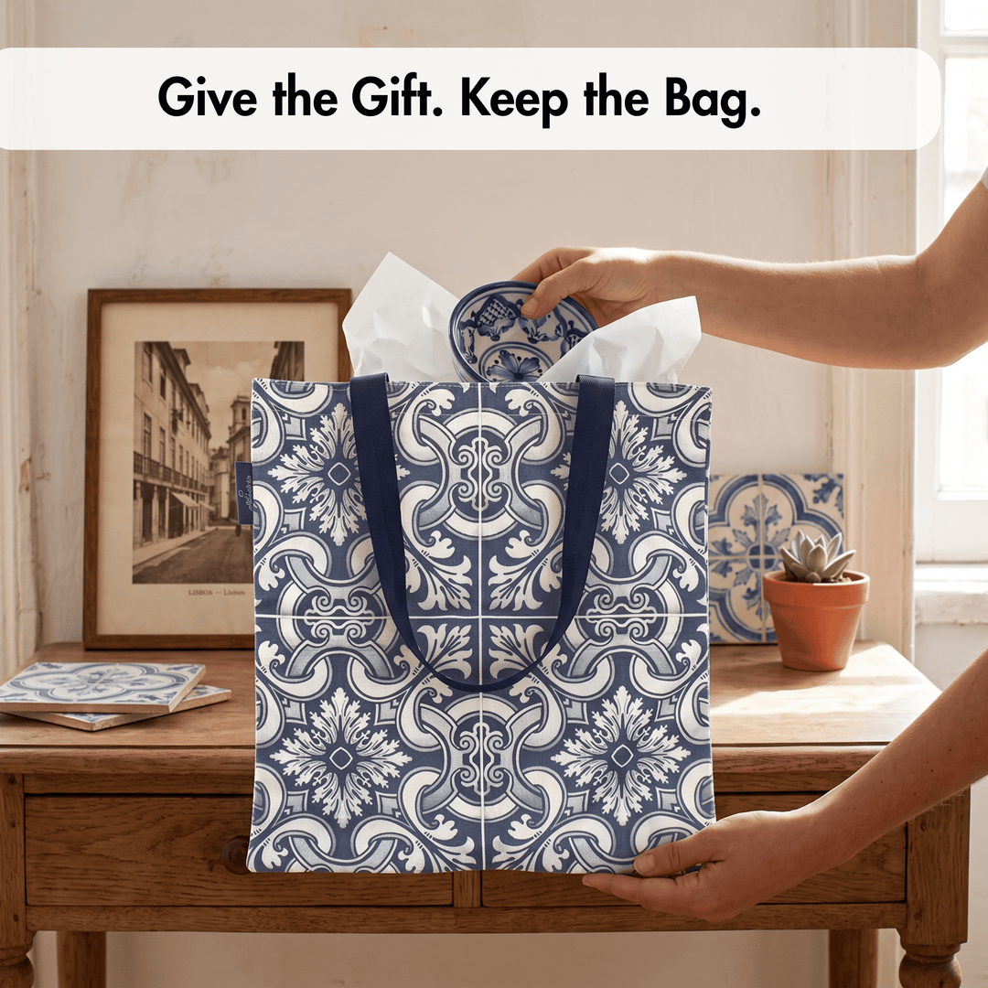 A navy blue and white patterned gift bag with dark blue handles stands on a wooden table in a home setting, with a person&