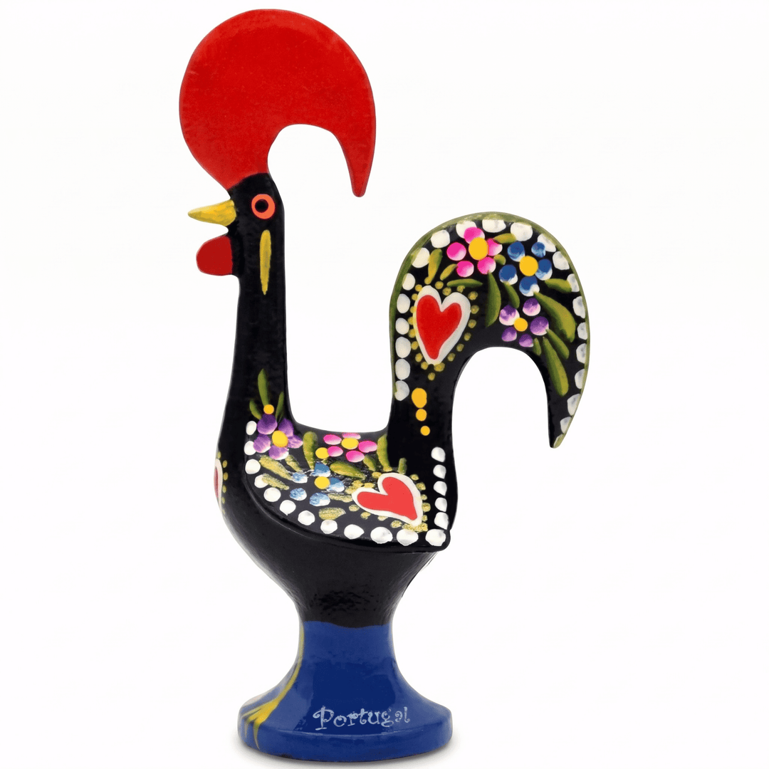 A hand-painted traditional Portuguese rooster figurine. The rooster features a glossy black body, a vibrant red comb and wattle, a blue pedestal base, and intricate multicolor floral patterns with red hearts on its neck and back.
