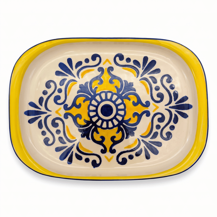 A rectangular ceramic serving platter with rounded corners, featuring a hand-painted Mediterranean style design with a yellow border, navy blue scrollwork, and a yellow central medallion on a cream-colored glaze.