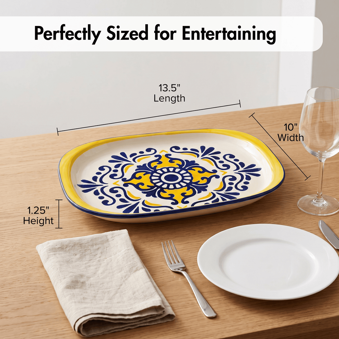 A decorative oval serving platter with a yellow and blue floral medallion pattern on a cream background, shown on a wooden table with size callouts reading 13.5 inches length, 10 inches width, and 1.