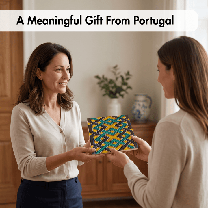 Two women in a warmly lit indoor setting exchange a square decorative tile featuring a colorful geometric pattern. A text banner at the top reads &