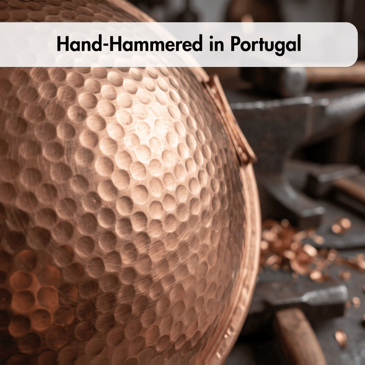 A close-up of a hammered copper-colored metal bowl or vessel with a textured dimpled surface, shown with the text &