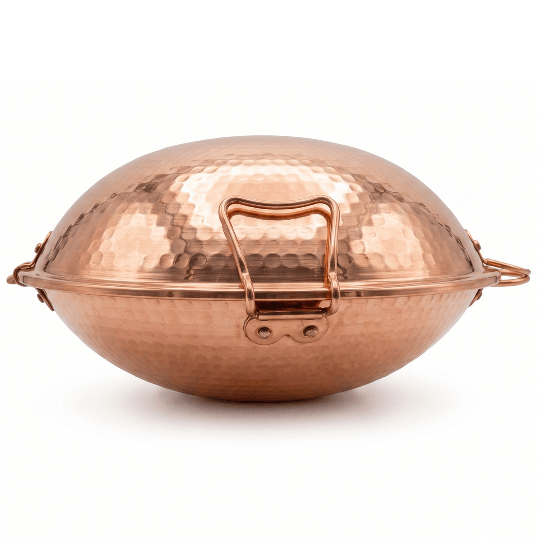 A hammered copper Portuguese Cataplana with a secure latch and side handles, shown on a clean white background.