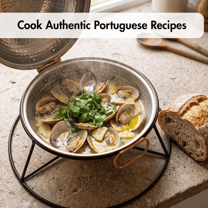 A Portuguese Cataplana on a black stand, filled with clams in a creamy yellow broth and topped with fresh green parsley, set on a stone countertop with a sliced loaf of bread and wooden spoons in the background. Text at the top reads &