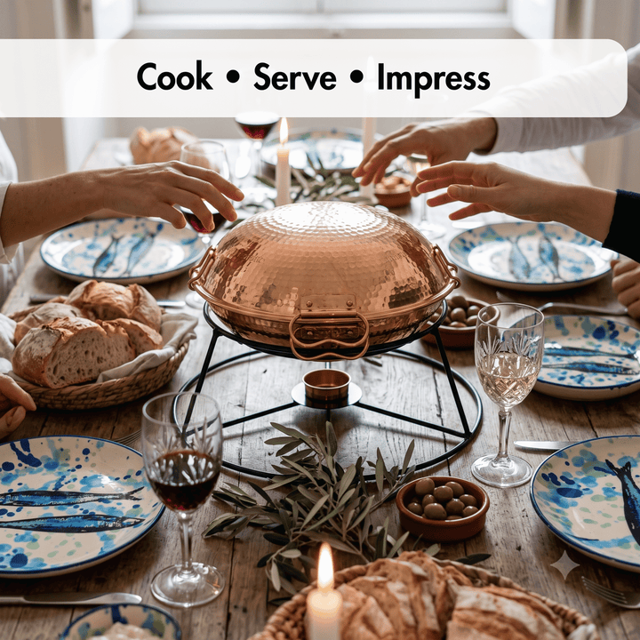 A Portuguese Cataplana on a black metal stand at a dining table, surrounded by blue and white patterned plates, bread, wine glasses, olives, and olive branches. A white banner at the top reads &