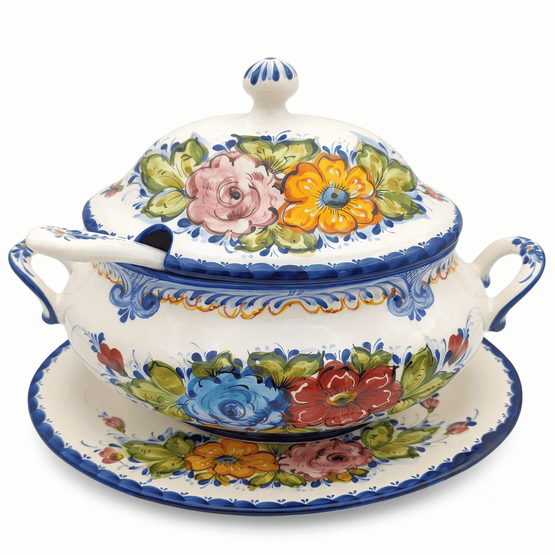 A hand-painted ceramic lidded soup dish with two side handles, a matching saucer, and a lid, decorated with vibrant floral motifs in pink, blue, red, yellow, and green on a white background.