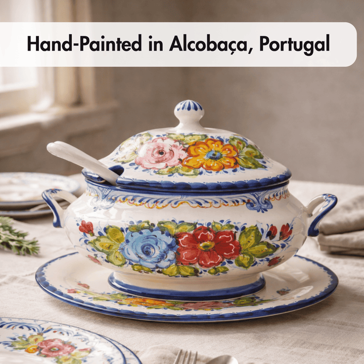 A hand-painted ceramic tureen with lid and matching saucer, decorated with colorful floral motifs and blue trim, set on a table. Text at the top reads &
