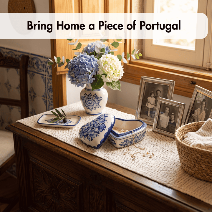 A styled interior scene shows a wooden table with a woven runner, a blue-and-white ceramic vase of flowers, a matching small decorative dish, a heart-shaped jewelry box, and framed vintage photos near a window. Text at the top reads, &