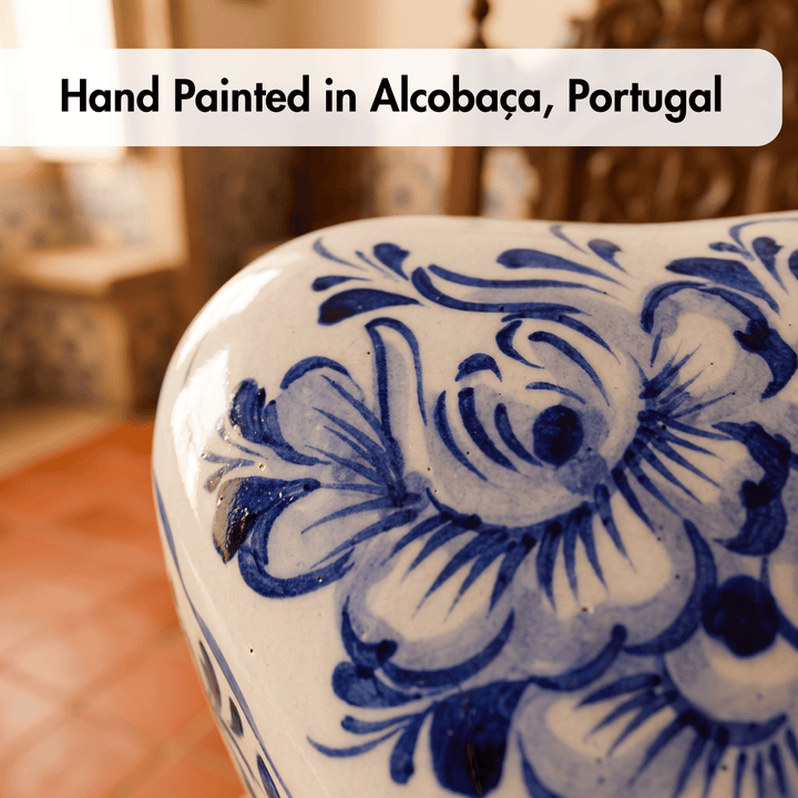 Close-up of a hand-painted ceramic vase or decorative pot with a blue floral pattern on a white glaze, with a text overlay reading &