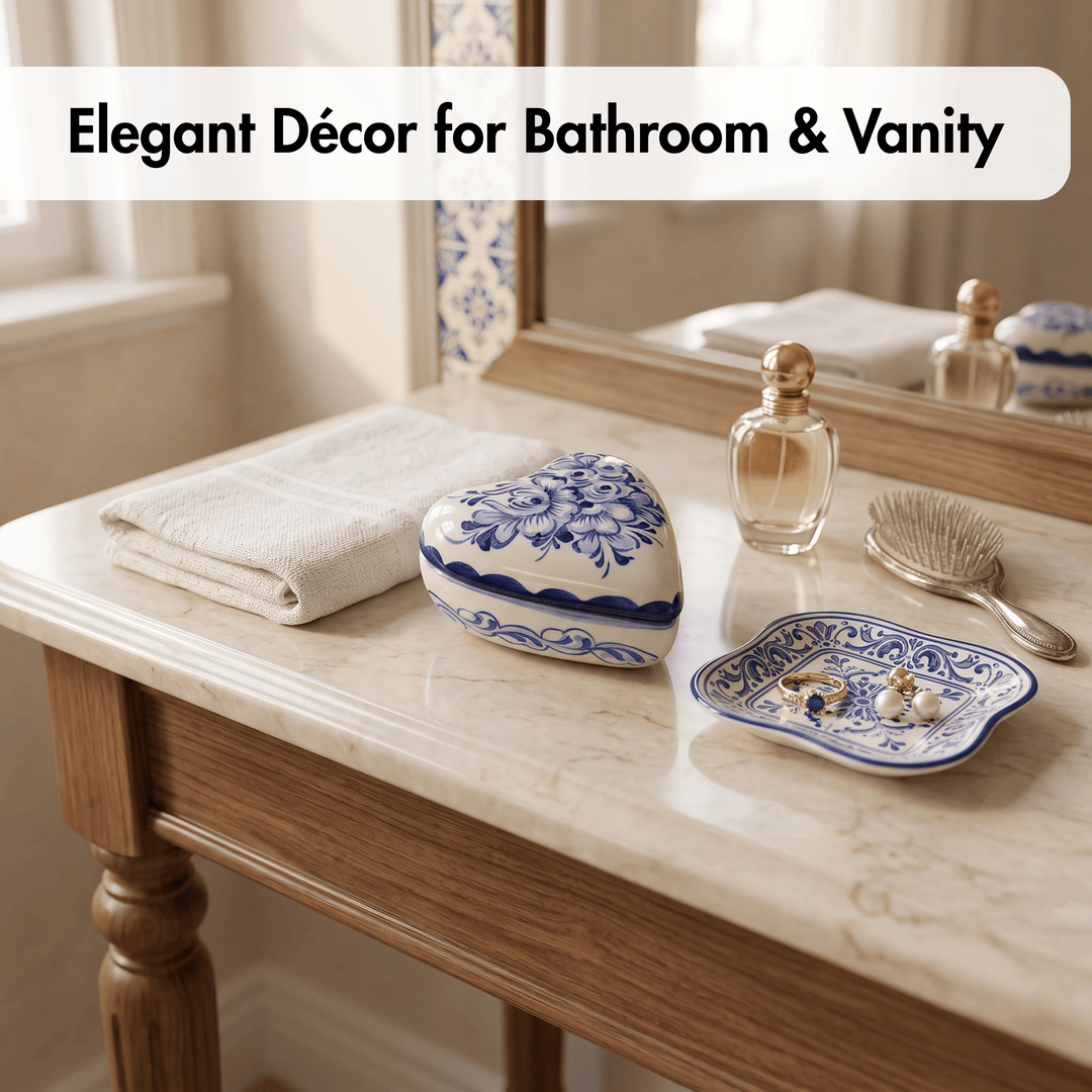 Blue and white porcelain bathroom vanity decor set on a marble countertop, including a heart-shaped box, a small dish, and a folded towel, with a mirror and perfume bottle reflected.