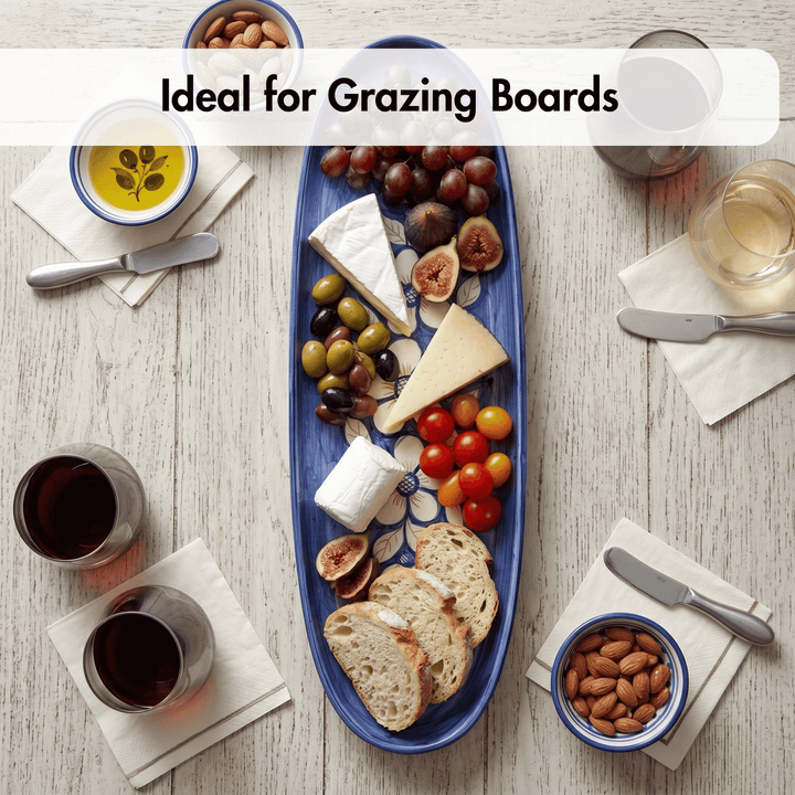 Blue grazing board with assorted foods on a wooden table with glasses of wine.