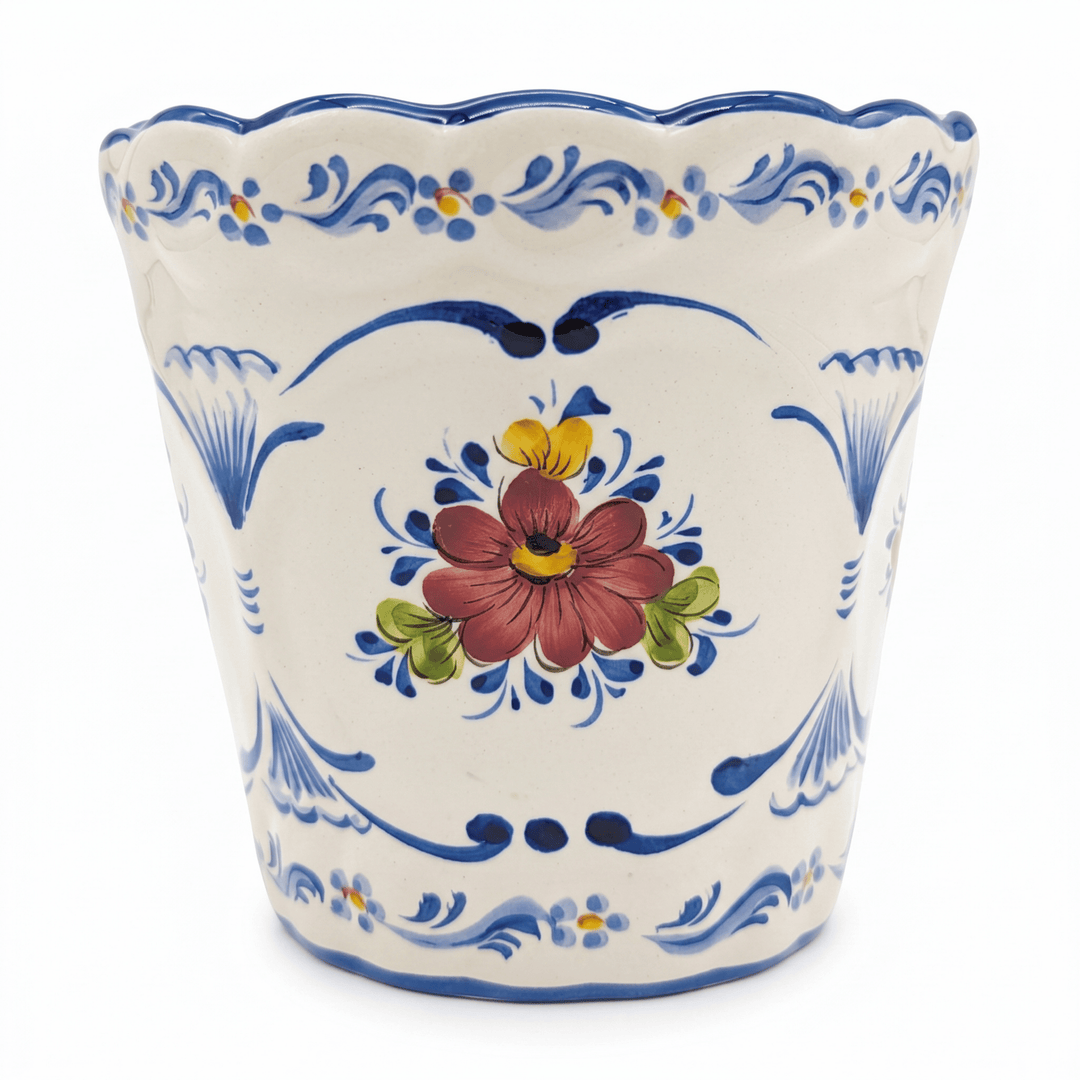 A hand-painted ceramic planter with a scalloped rim, featuring a central red and yellow flower motif surrounded by blue scrollwork and floral patterns on a white background.