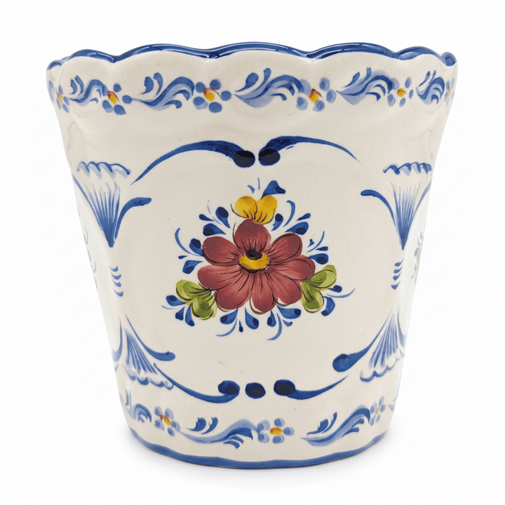 A hand-painted ceramic planter with a scalloped rim, featuring a central red and yellow flower motif surrounded by blue scrollwork and floral patterns on a white background.