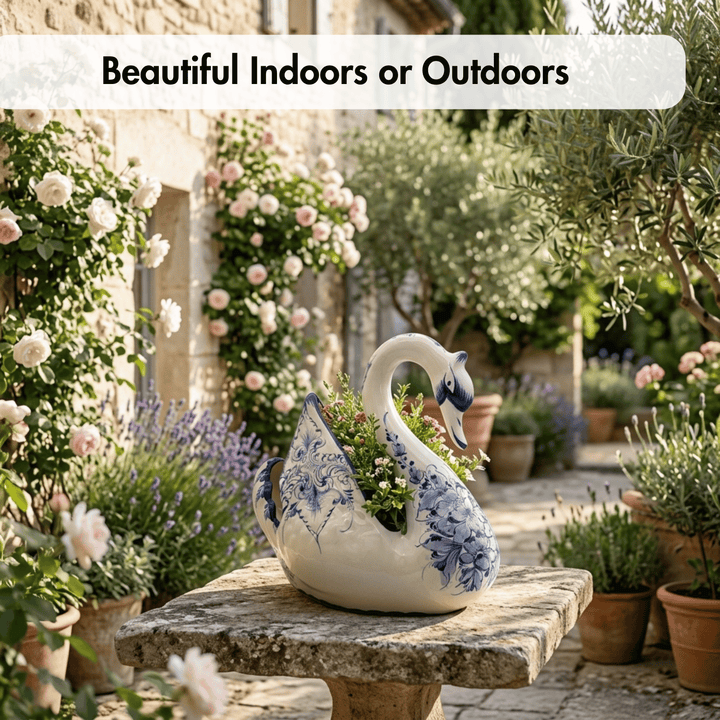 A decorative ceramic swan-shaped planter with blue floral detailing, filled with green foliage, displayed on a stone garden bench in a lush, sunlit garden courtyard.