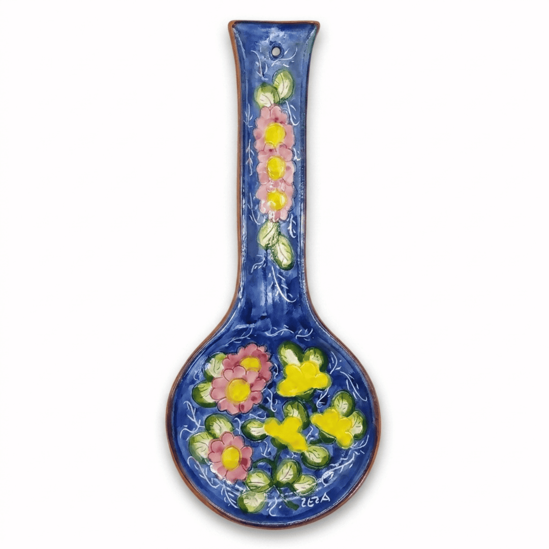 A ceramic wall spoon rest with a long handle, decorated with a glossy blue glaze and colorful hand-painted floral motifs in pink, yellow, and green, shown against a plain white background.