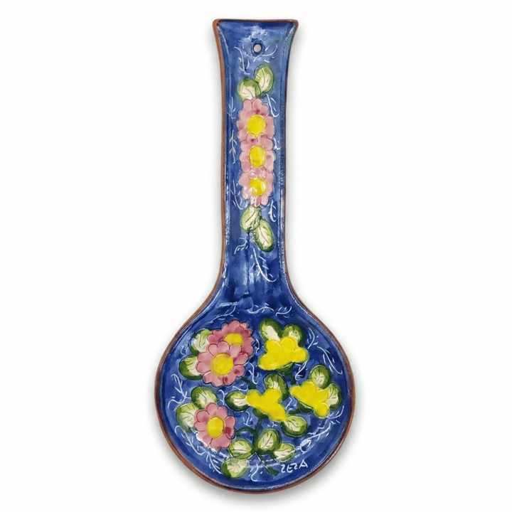 A ceramic wall spoon rest with a long handle, decorated with a glossy blue glaze and colorful hand-painted floral motifs in pink, yellow, and green, shown against a plain white background.