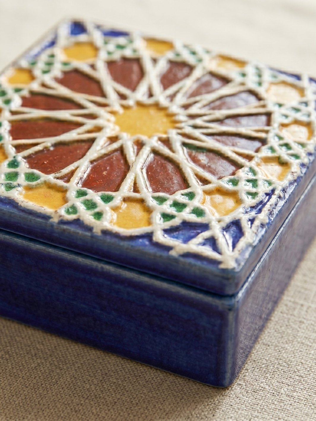 Decorative ceramic box with geometric pattern on a beige surface