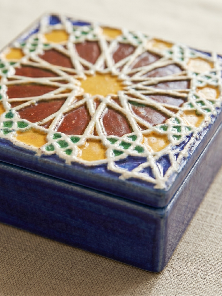 Decorative ceramic box with geometric pattern on a beige surface