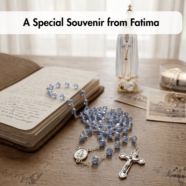 Blue rosary on an open book with a statue and candles in the background, labeled 'A Special Souvenir from Fatima'.