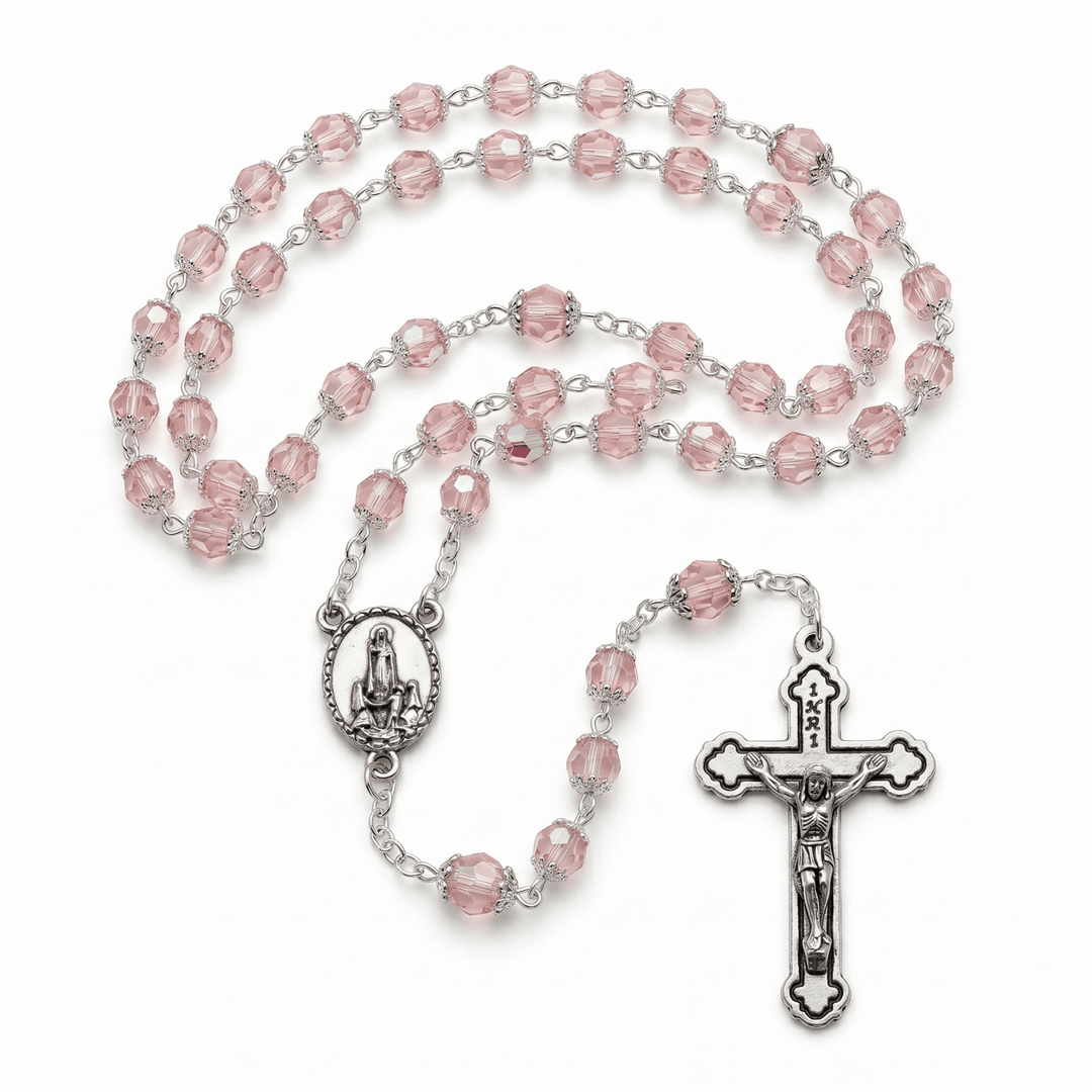Pink rosary with silver crucifix and center piece on a white background