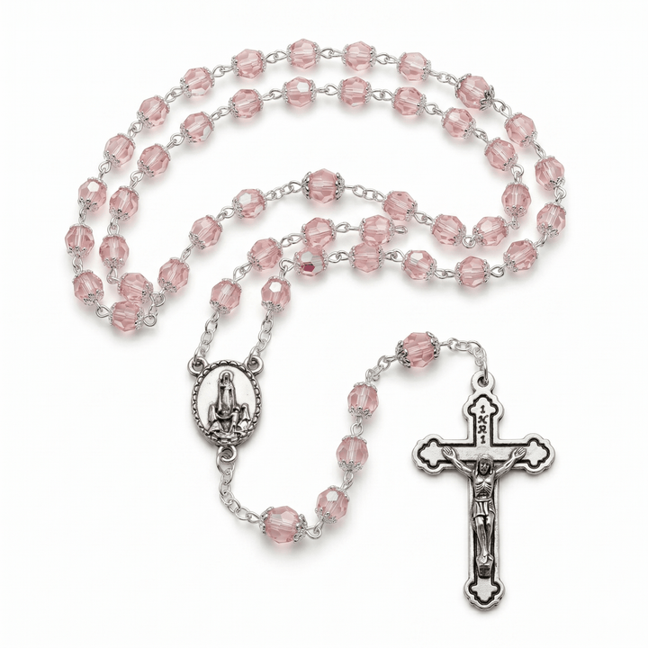 Pink rosary with silver crucifix and center piece on a white background
