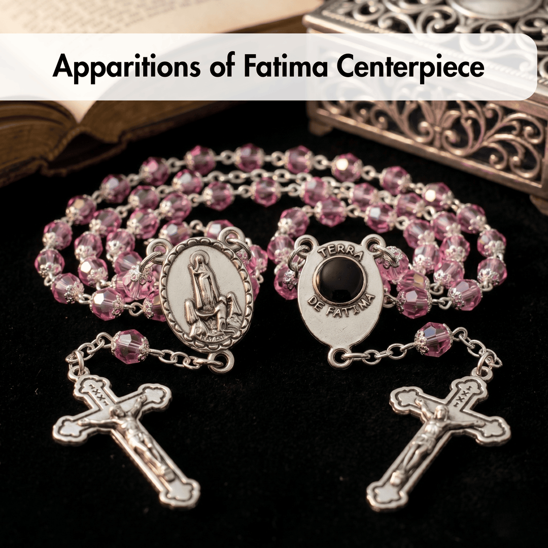Pink rosary with silver beads and crucifixes on a dark background