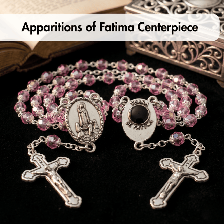 Pink rosary with silver beads and crucifixes on a dark background
