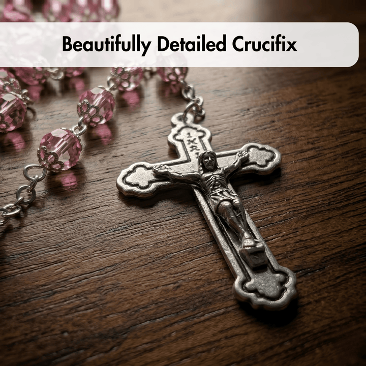 Beautifully detailed crucifix with pink beads on a wooden surface
