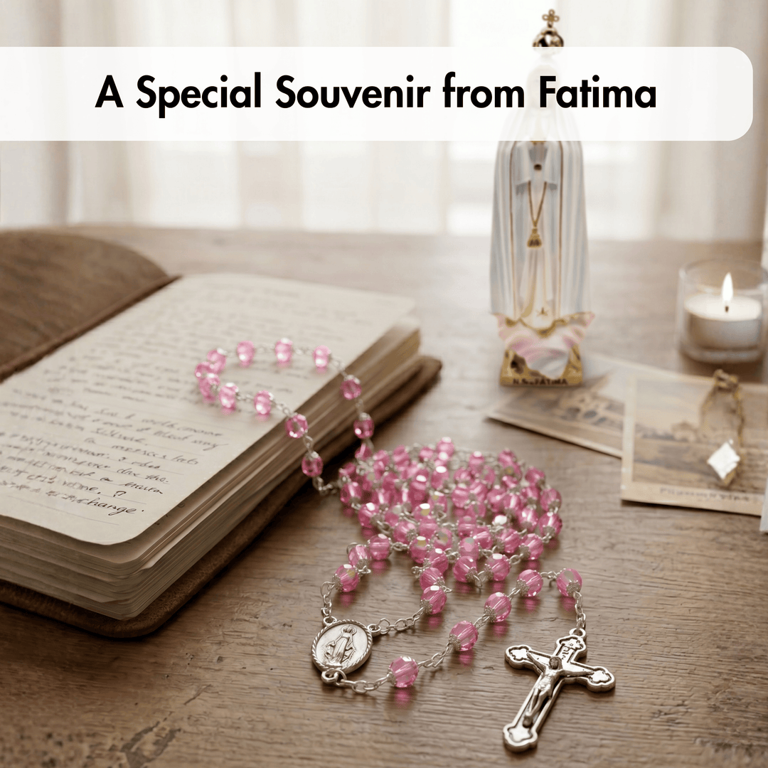 Pink rosary on an open book with a candle and decorative items in the background.