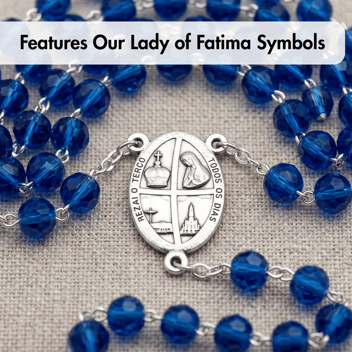 Blue rosary with silver Our Lady of Fatima symbols on a textured fabric background
