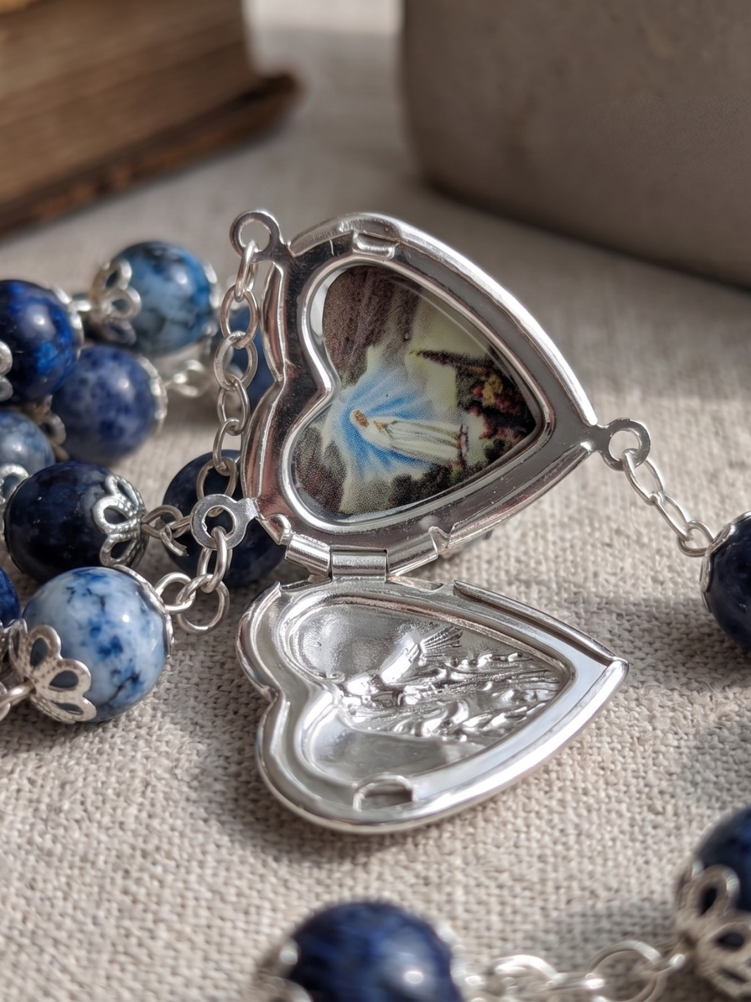 Heart-shaped locket with blue beads on a textured surface